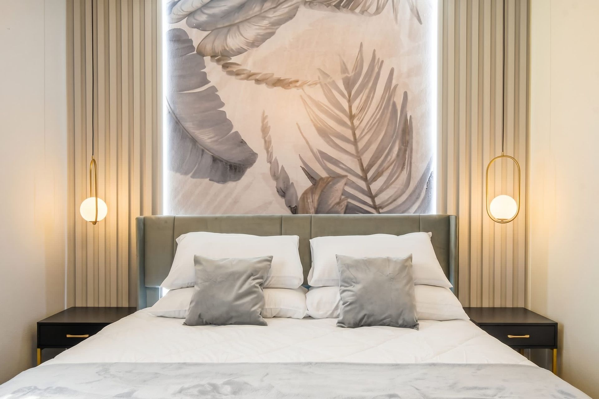 Elegant king bed with layered pillows, modern lighting, and nature-inspired art.