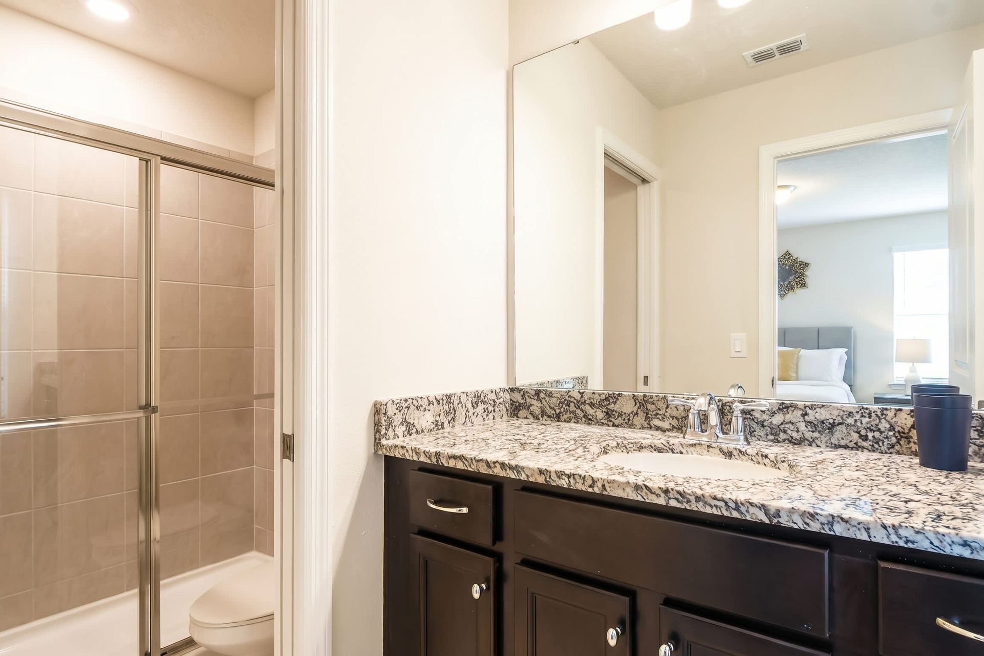 Modern bathroom with granite vanity, walk-in shower, and direct bedroom access.