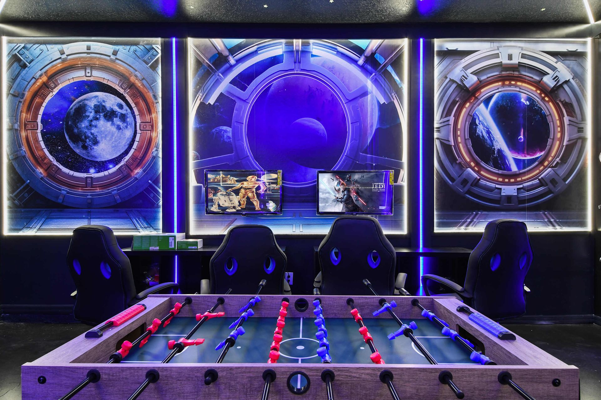 Space-themed gaming room with foosball, dual screens, and immersive galactic art.