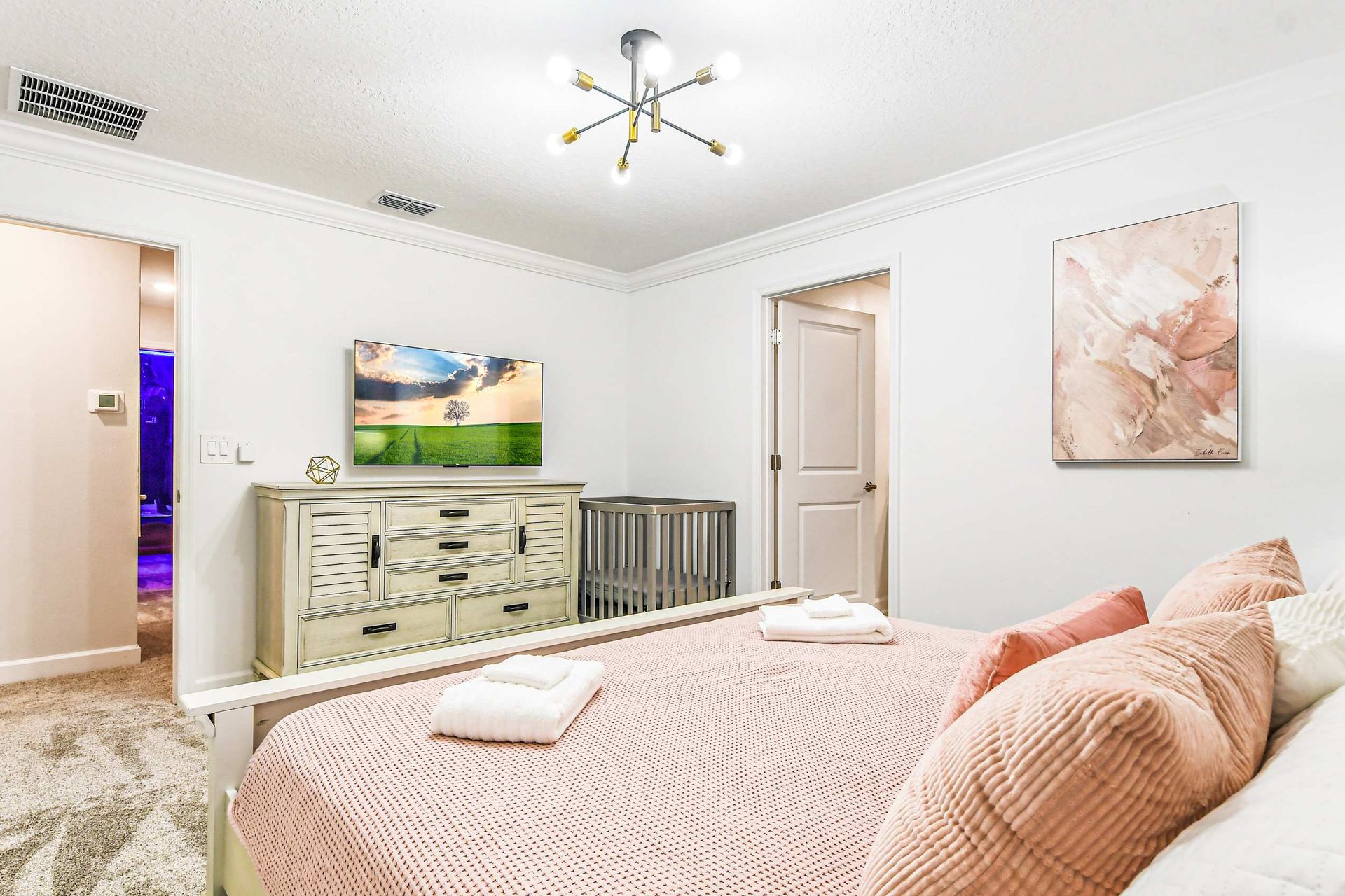 Opulent master bedroom boasts a spacious king bed, complemented by a crib for added comfort