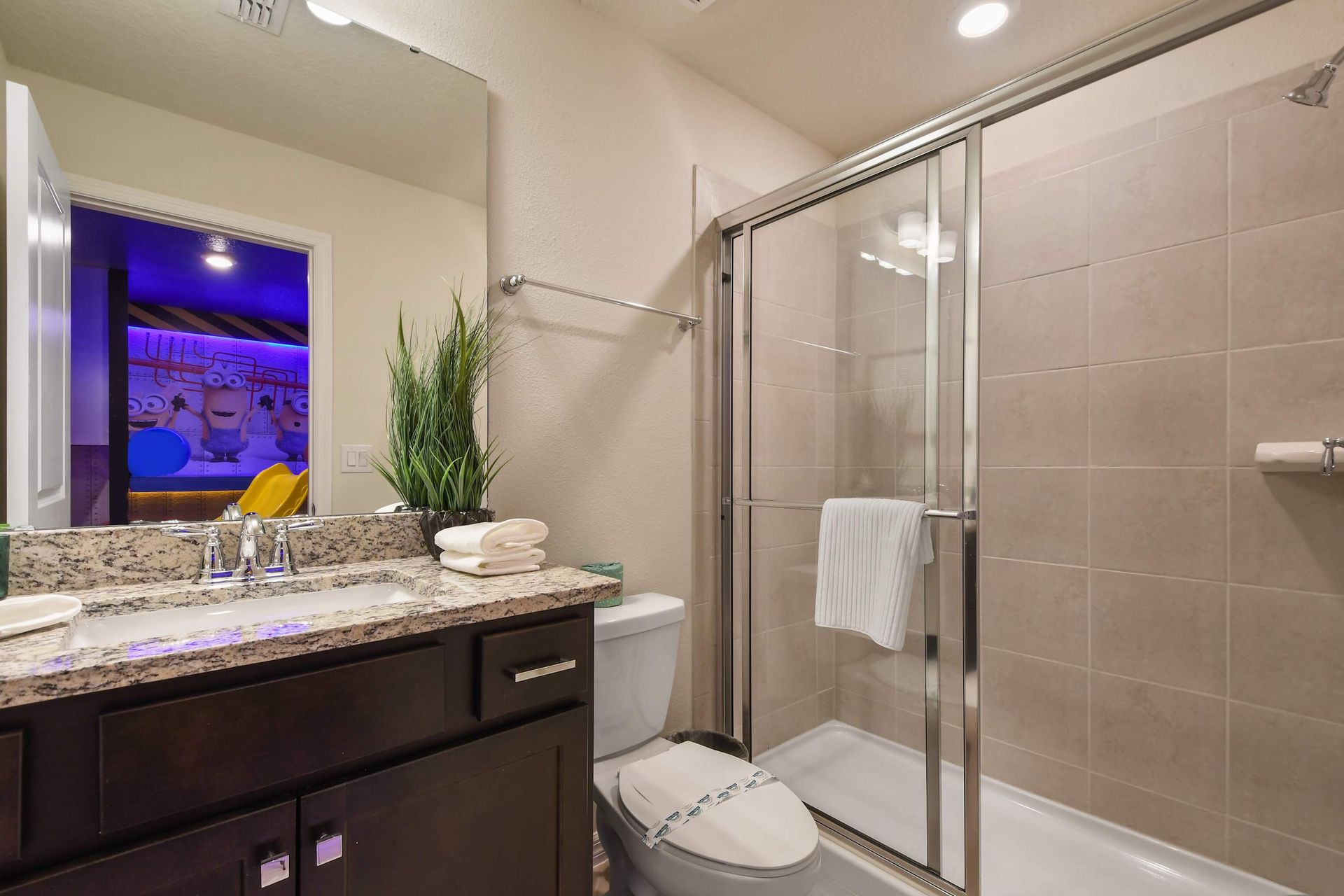 Bright bathroom with granite countertop, tiled shower, and natural light.