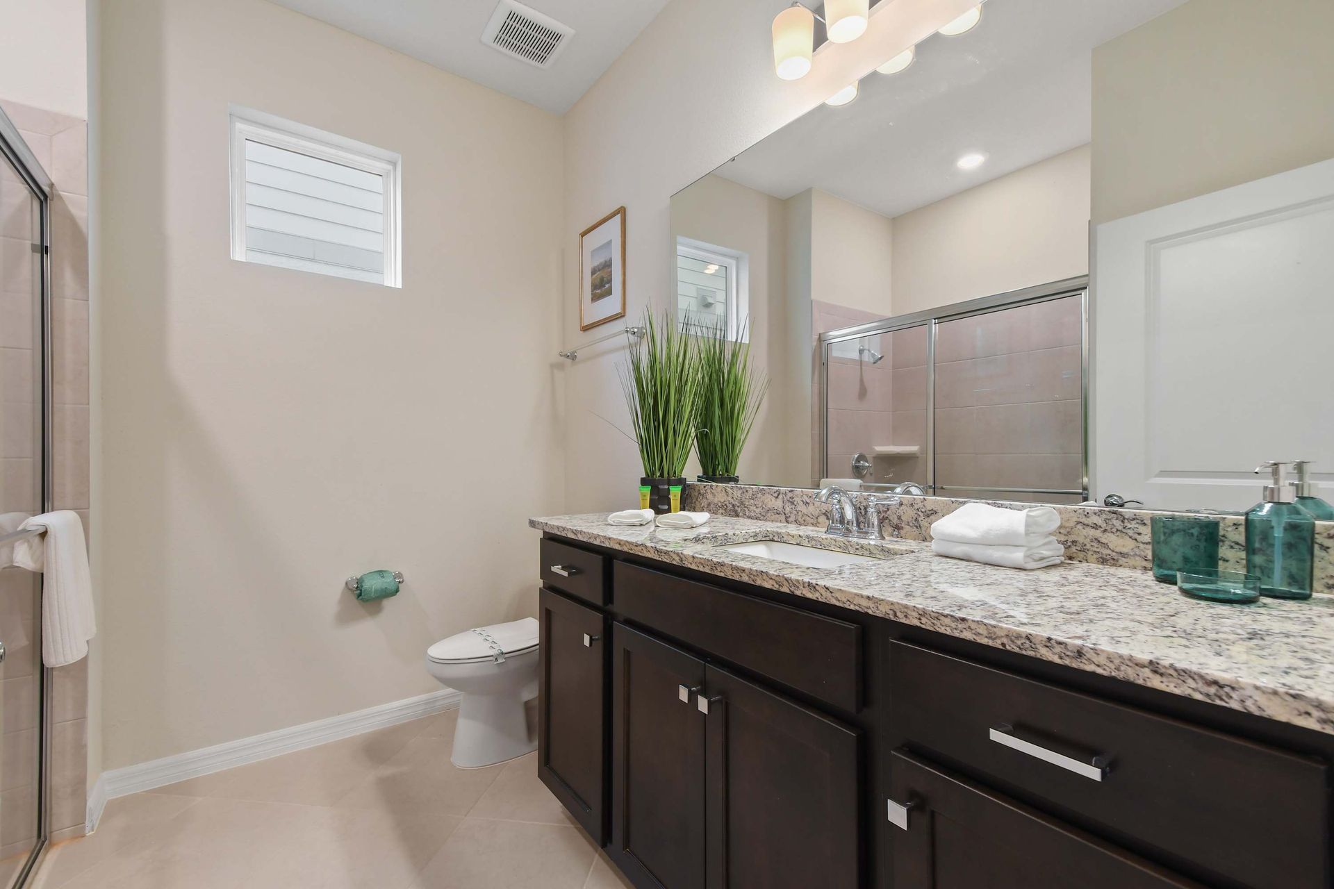 Elegant bathroom with granite vanity, walk-in shower, and art decor.