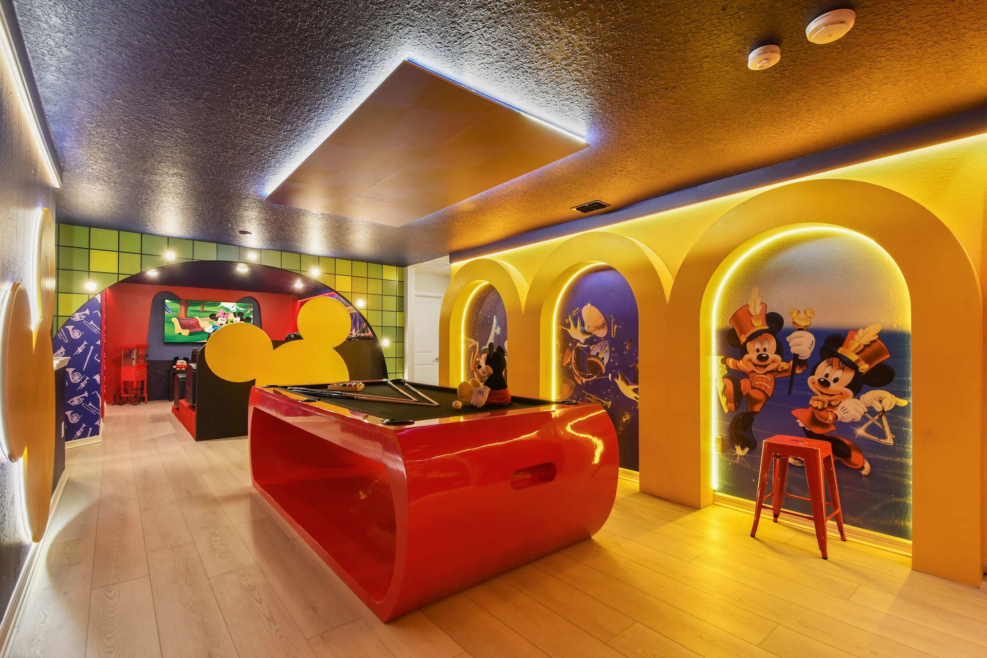 Vibrant Mickey-themed game room with pool table & arcade fun!