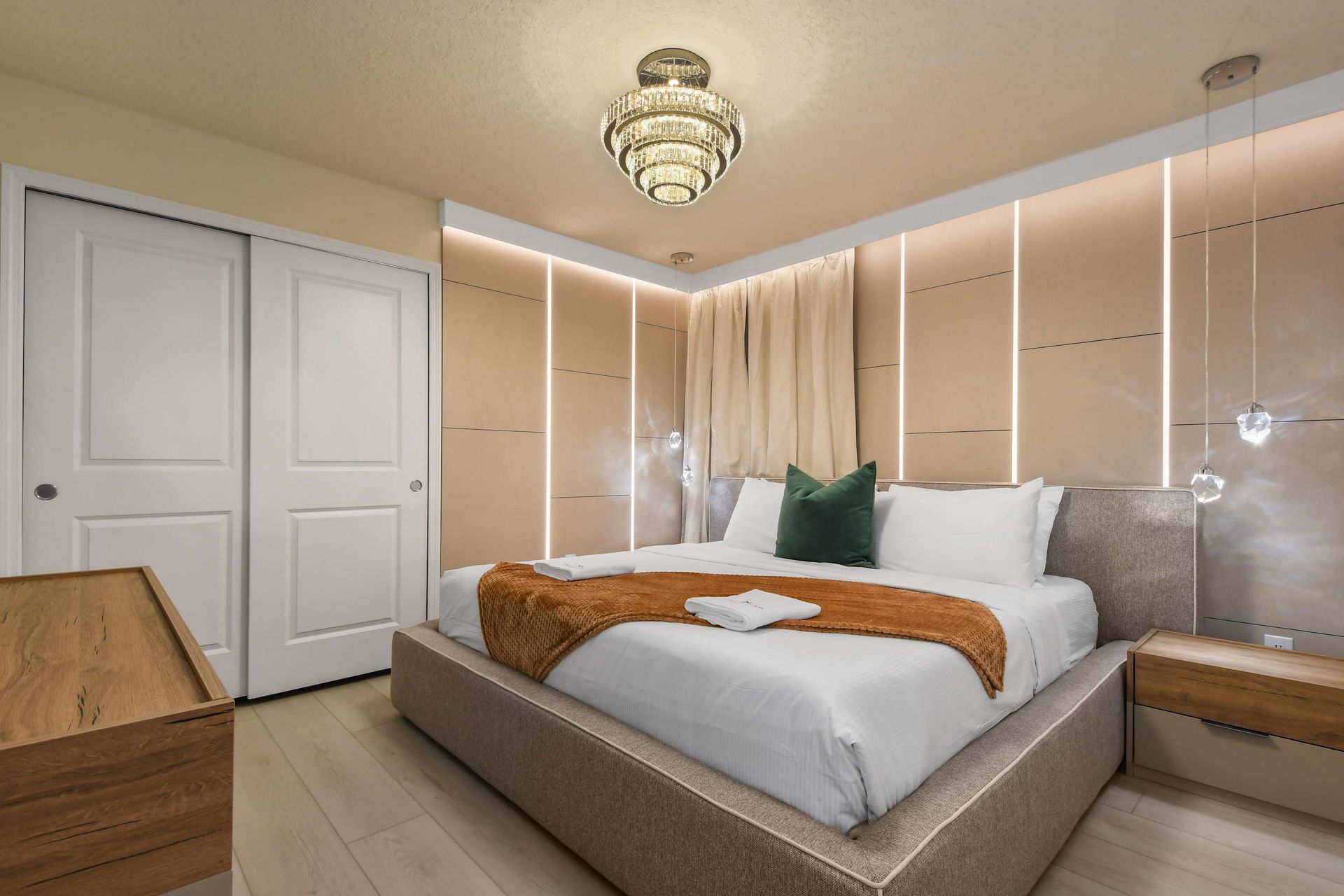 Elegant bedroom with warm tones, crystal lighting, and cozy charm.