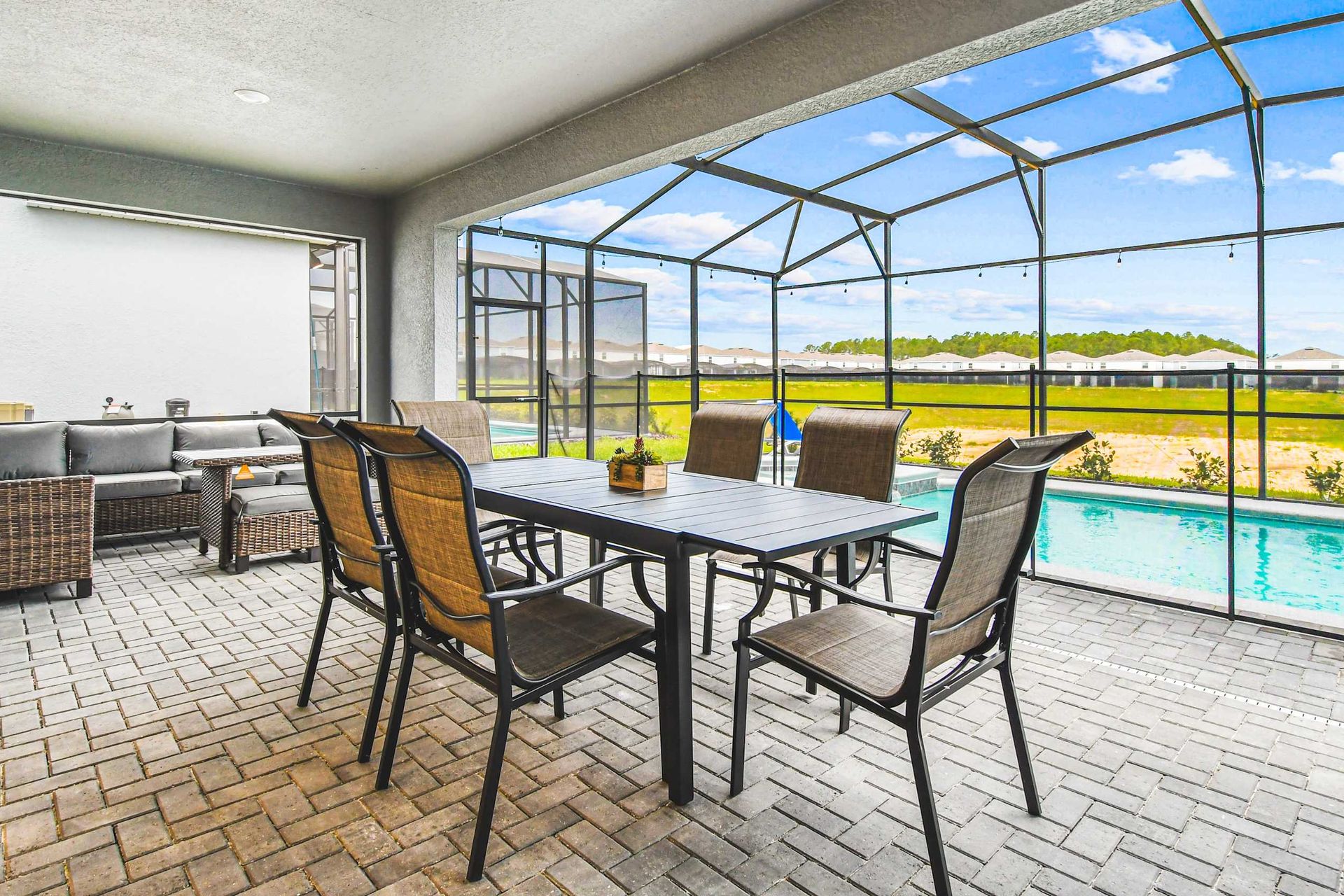 Spacious lanai with screened pool, comfy lounge seating, and alfresco dining setup.