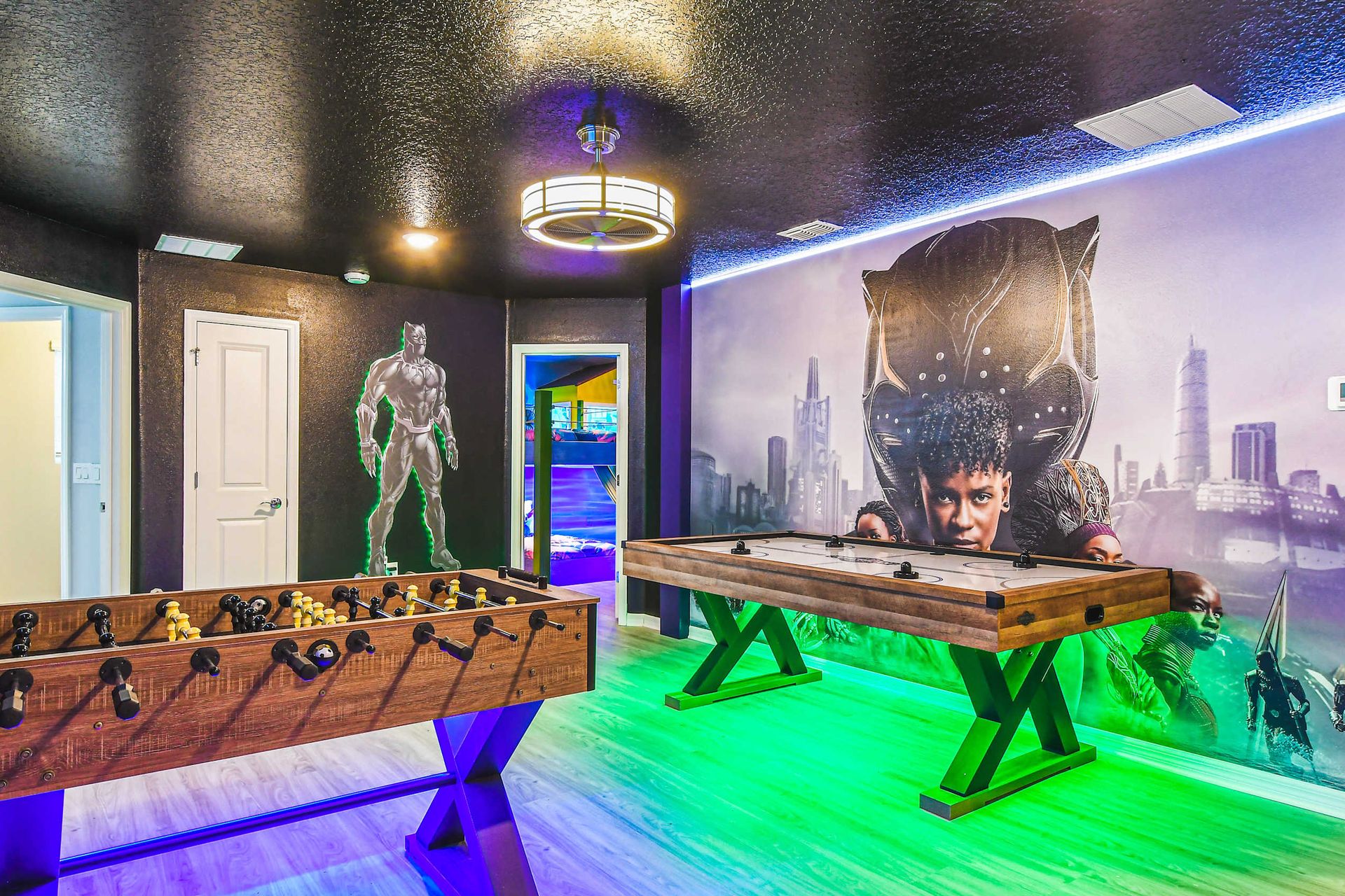 Superhero-themed game room with foosball, air hockey, and vibrant wall art.