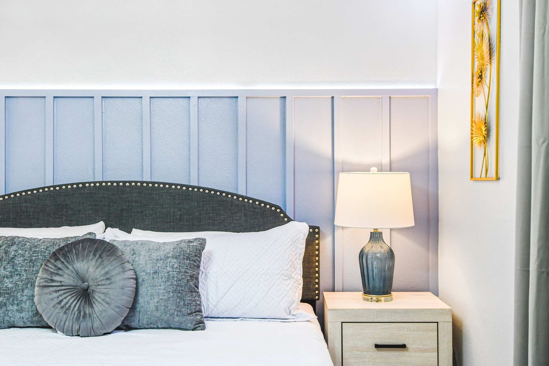 Cozy bedroom with soft blue paneling, elegant gray accents, and warm bedside lighting.