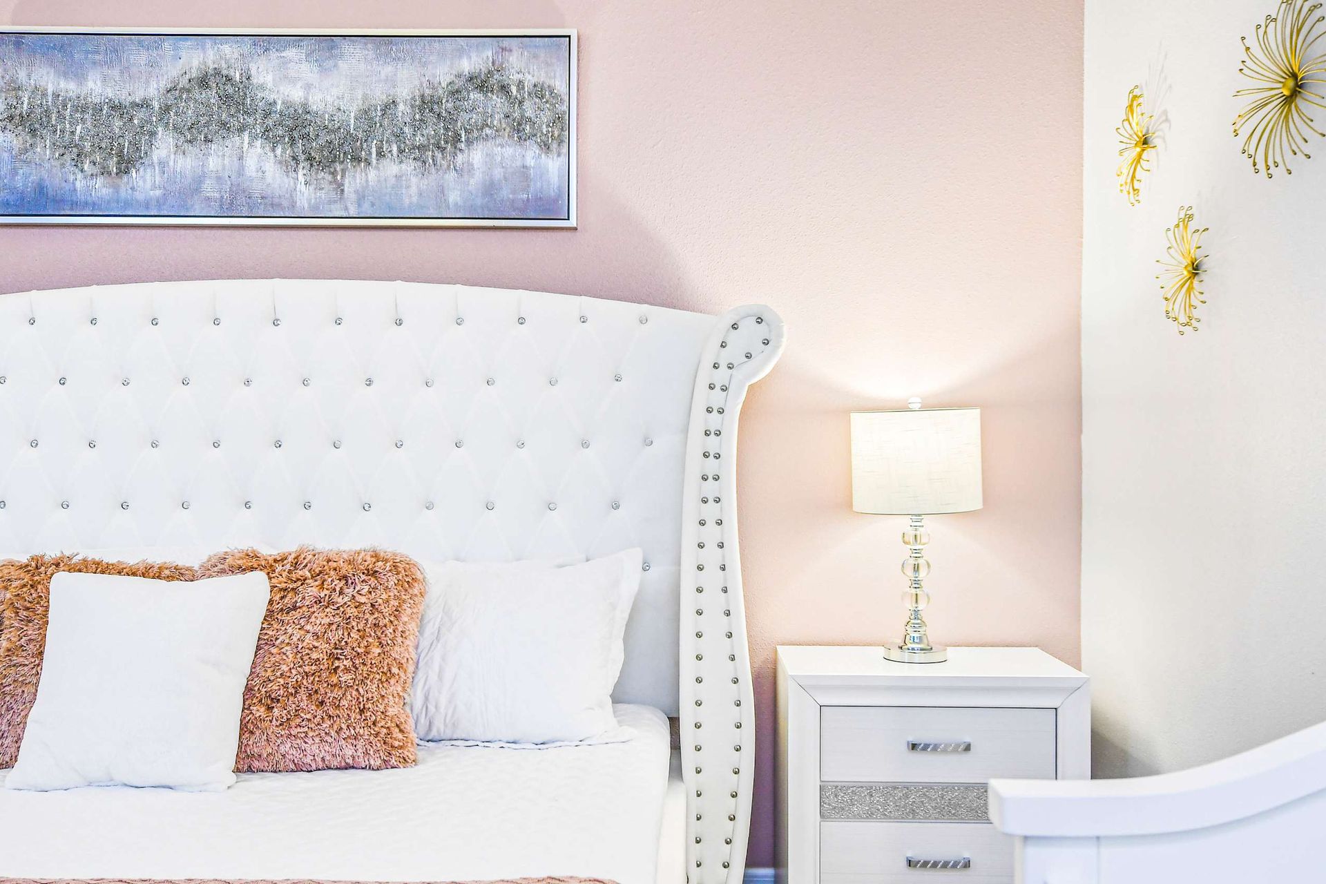 Serene bedroom with tufted headboard, soft blush tones, and elegant gold accents.