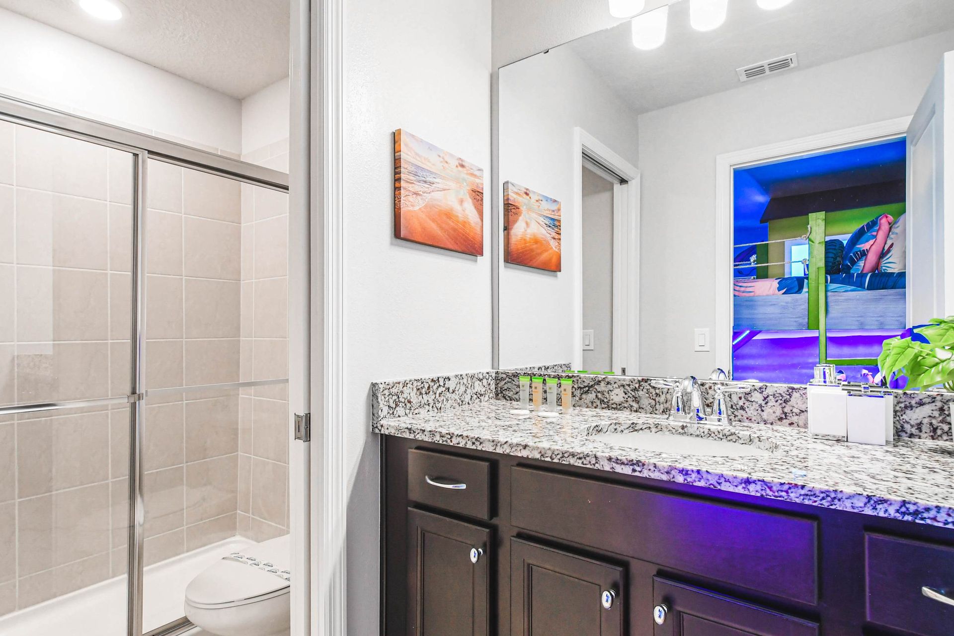 Bright shared bathroom with granite counters, dual sinks, and a sleek glass shower.
