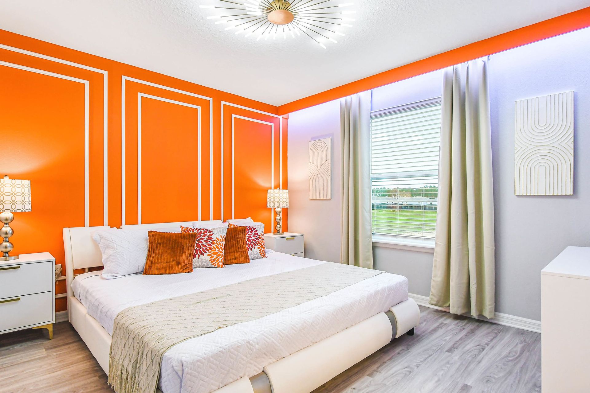 Bold orange accent wall meets cozy elegance in this bright and modern retreat.