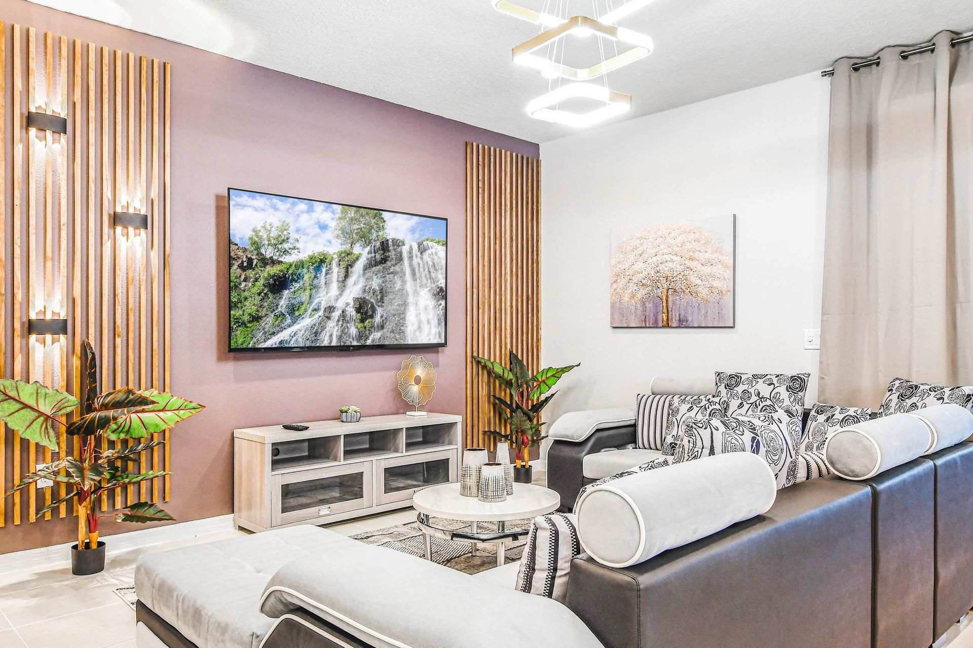 Modern living room with plush seating, accent lighting, and a serene waterfall view.