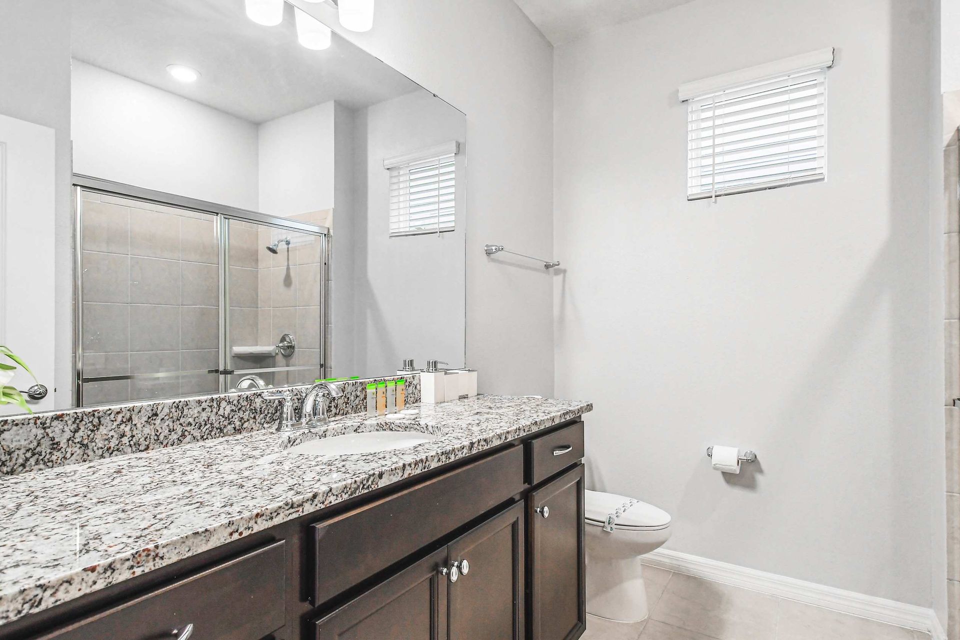 Stylish full bathroom with granite counters and a spacious glass shower.