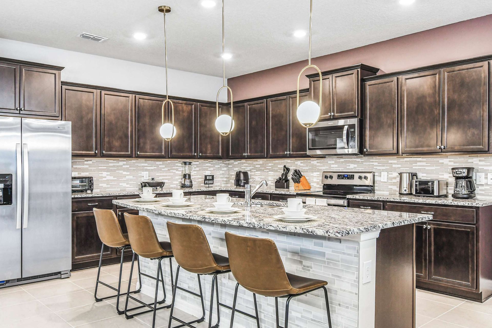 Sleek modern kitchen with granite island, stainless appliances, and pendant lighting.