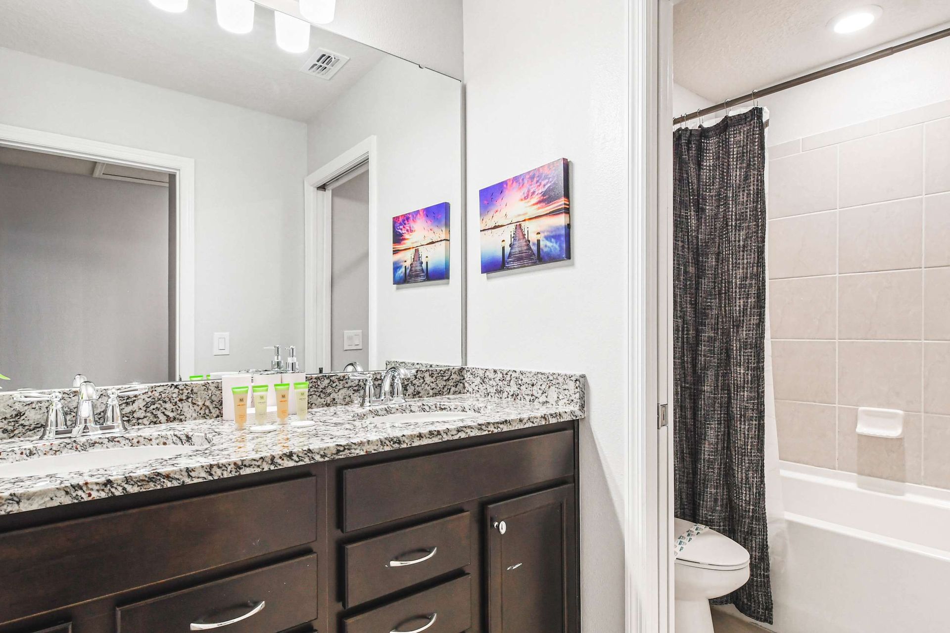 Modern bathroom with granite vanity, tub/shower combo, and sleek contemporary style.