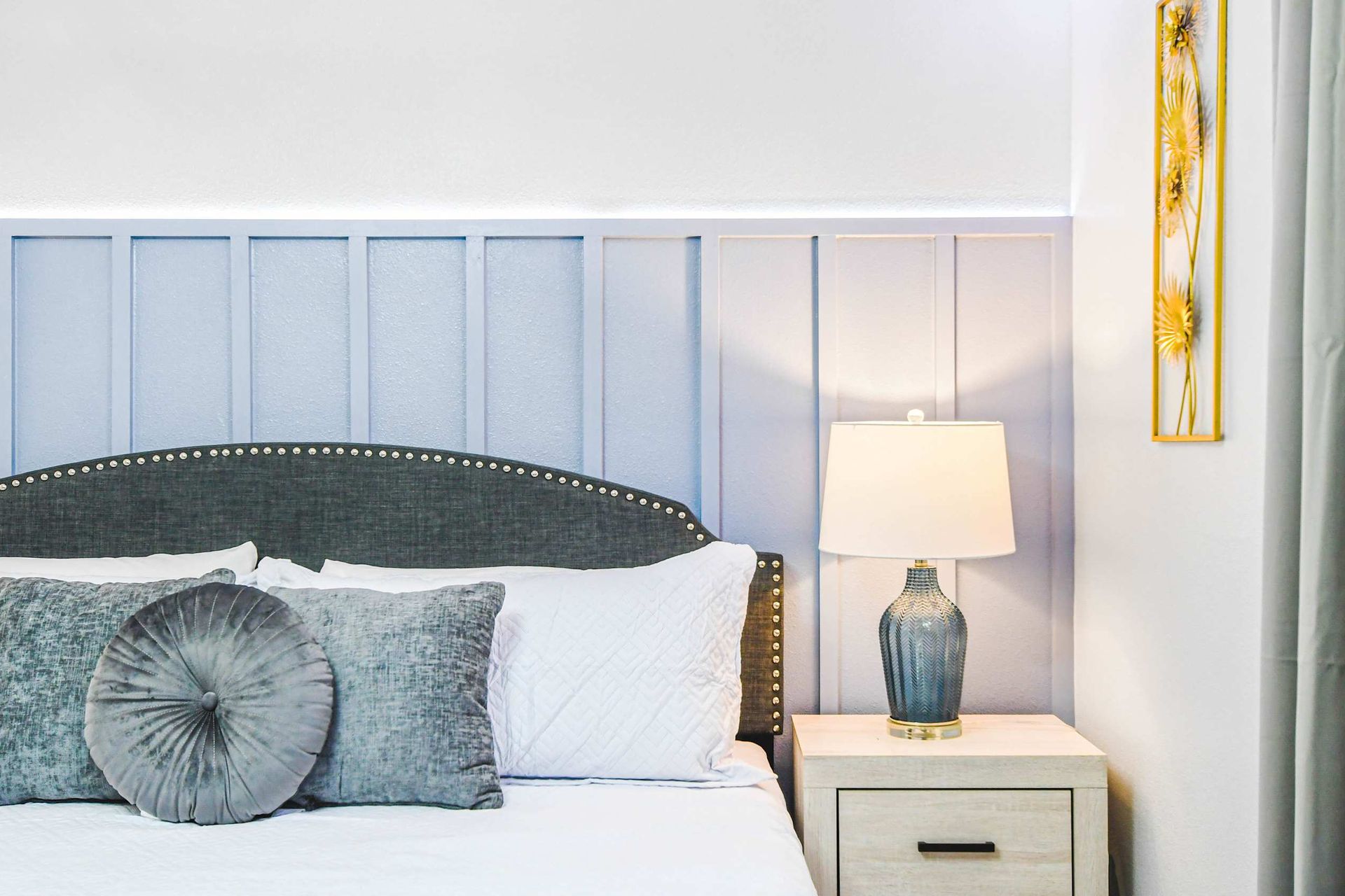 Cozy bedroom with soft blue paneling, elegant gray accents, and warm bedside lighting.