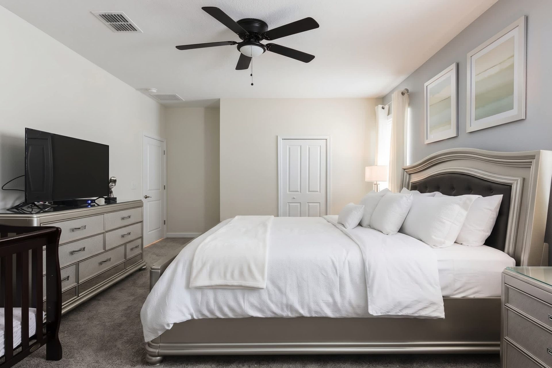 Spacious king bedroom with TV, elegant decor, and a convenient crib for families.