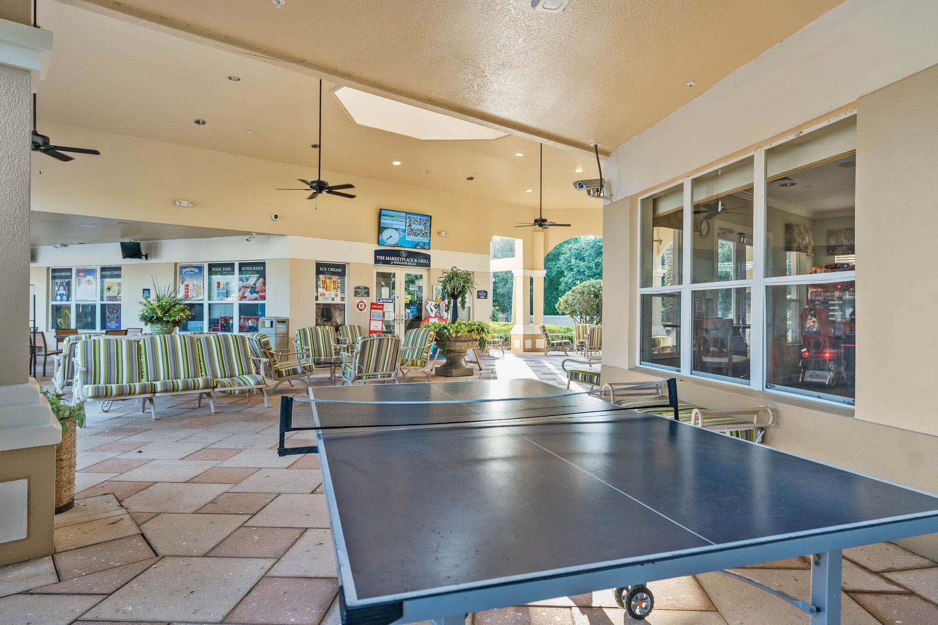 Sun-drenched resort terrace featuring a pro-grade ping pong table and vibrant lounge seating.