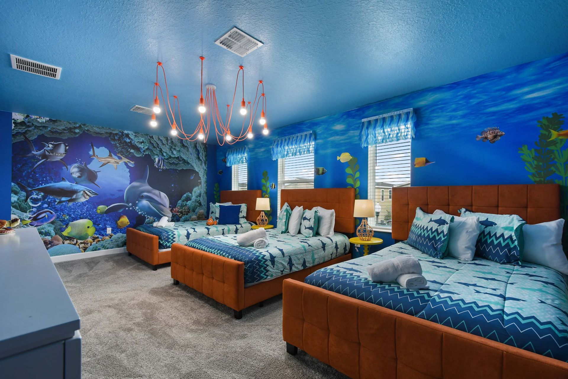 Underwater-themed bedroom with vibrant ocean mural, cozy beds, and playful decor