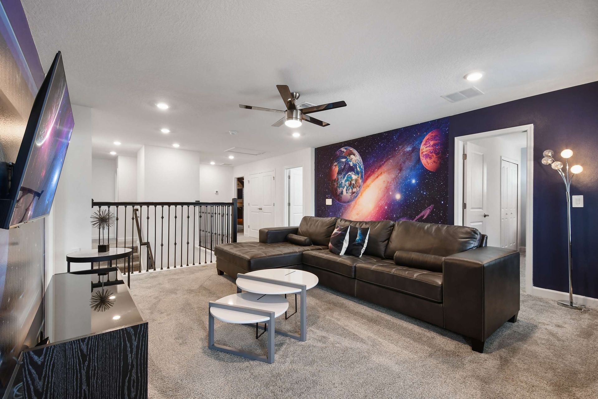 Spacious loft with galaxy wall art, cozy sectional, and a sleek entertainment setup.
