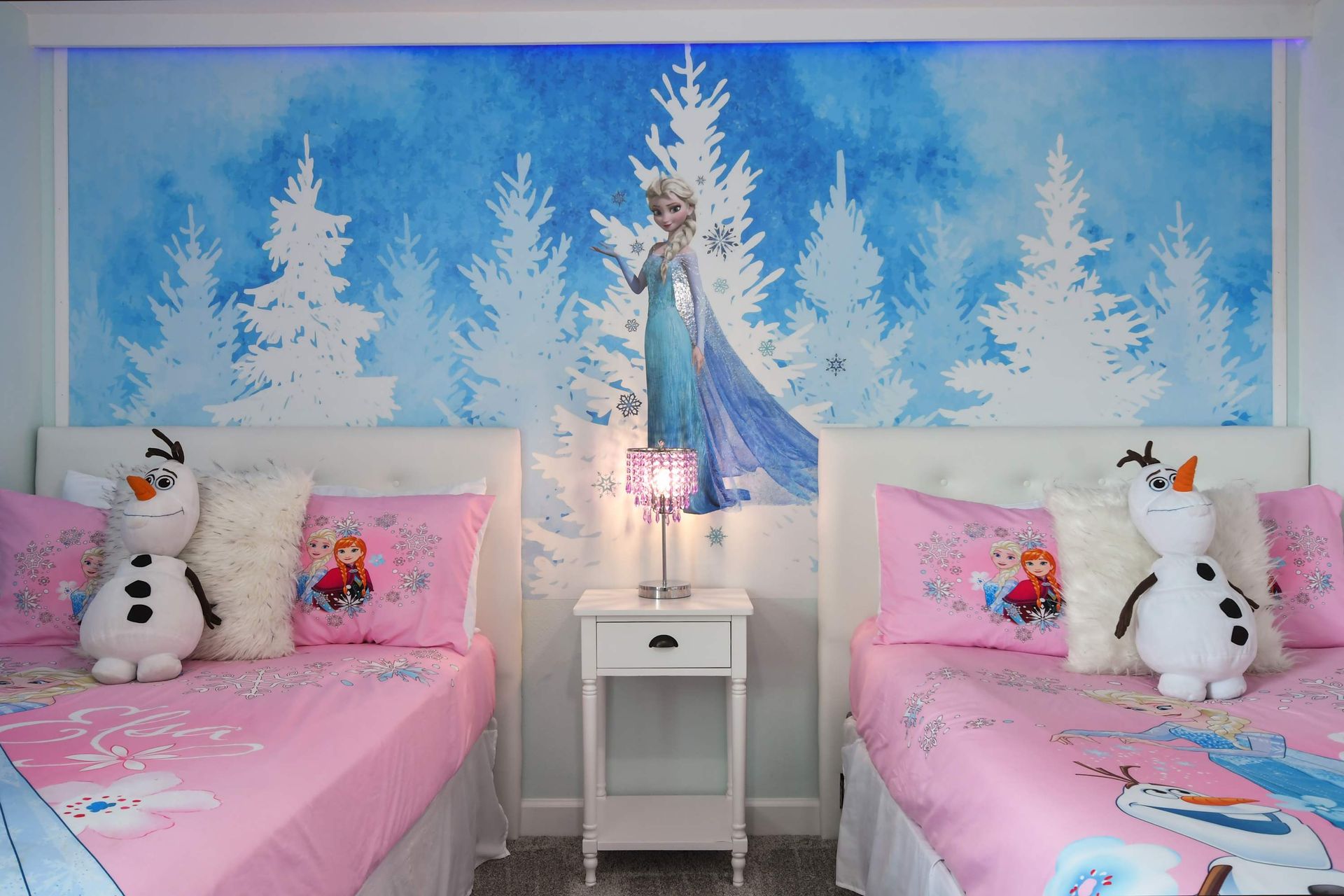 Whimsical Frozen-themed kids’ room with two beds, bright murals, and cozy charm.

