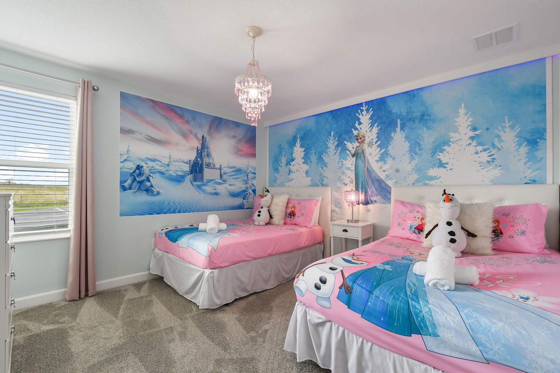 Whimsical Frozen-themed kids’ room with two beds, bright murals, and cozy charm.
