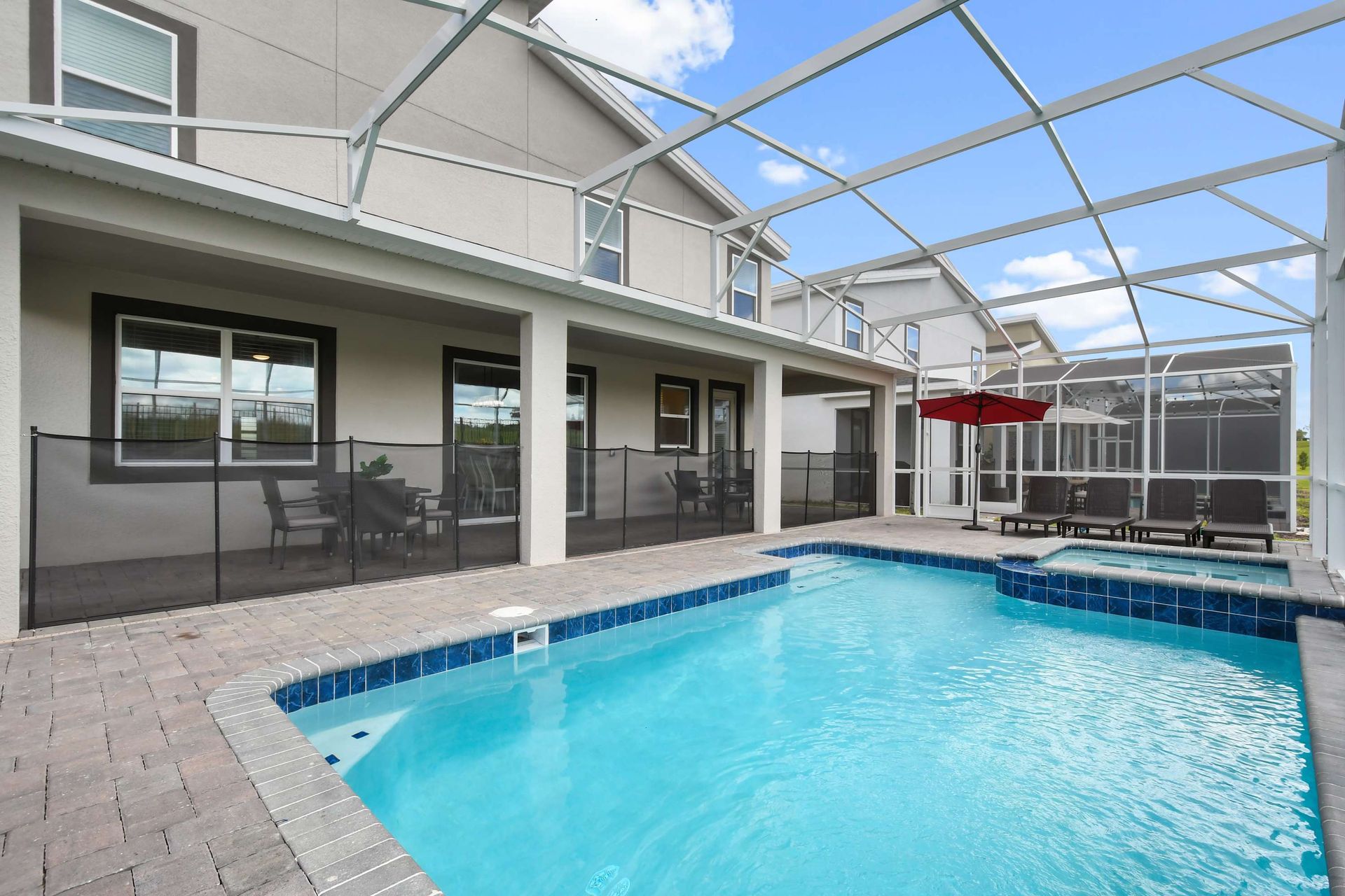 Spacious screened-in pool and spa with covered patio and family-friendly safety fence.
