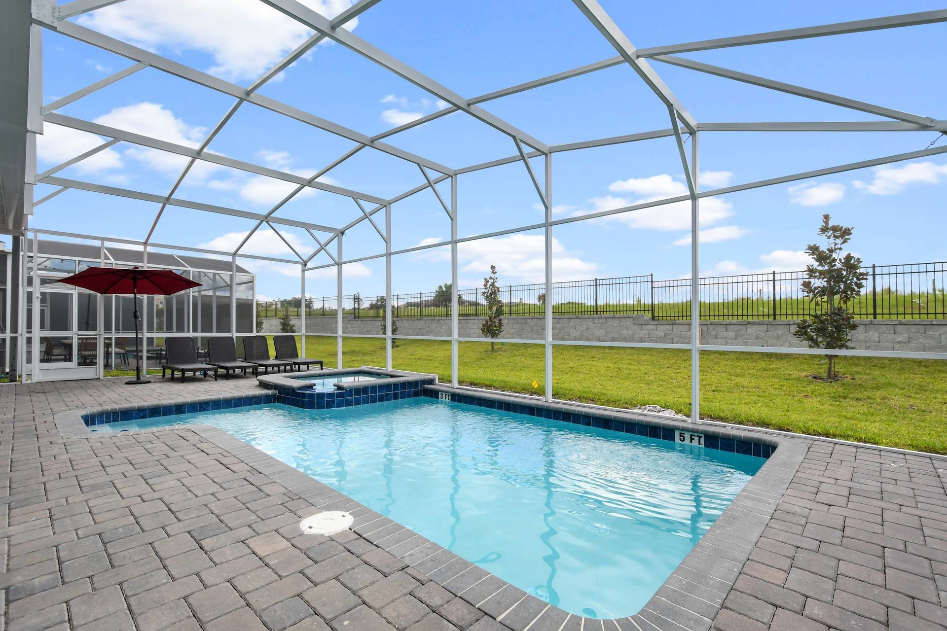 Spacious screened-in pool and spa with sunny skies and peaceful outdoor seating.
