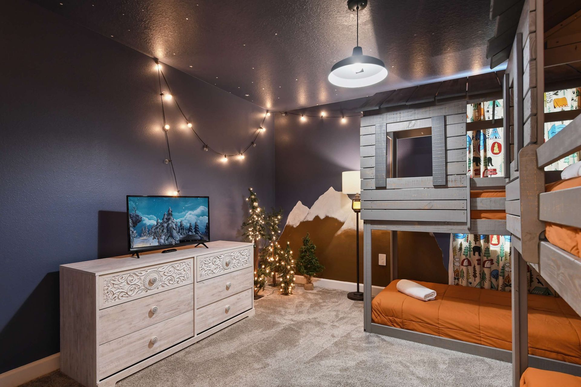 Adventure-themed bunk room with starry ceiling, cozy cabin beds, and a crib included.
