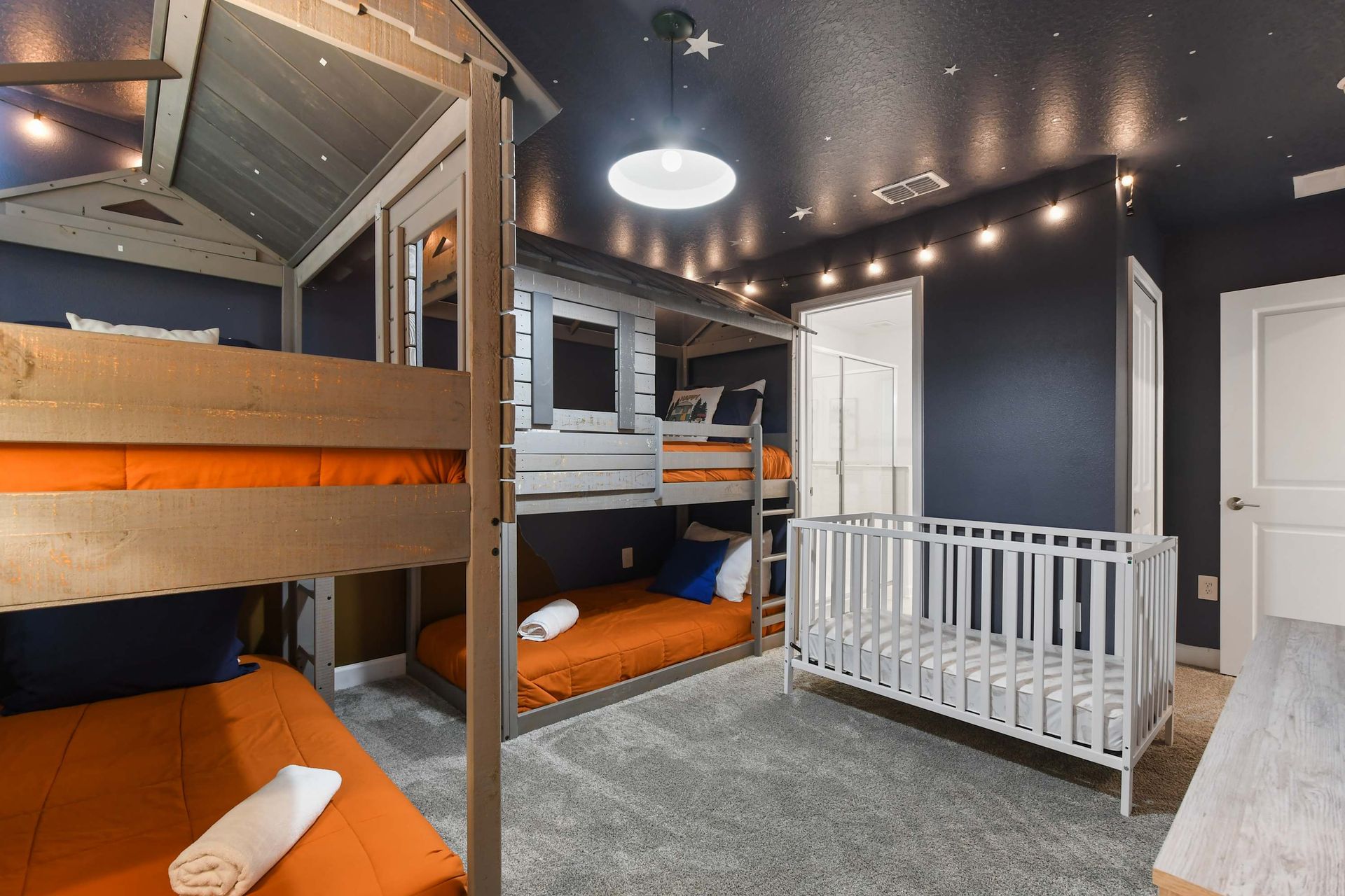 Adventure-themed bunk room with starry ceiling, cozy cabin beds, and a crib included.
