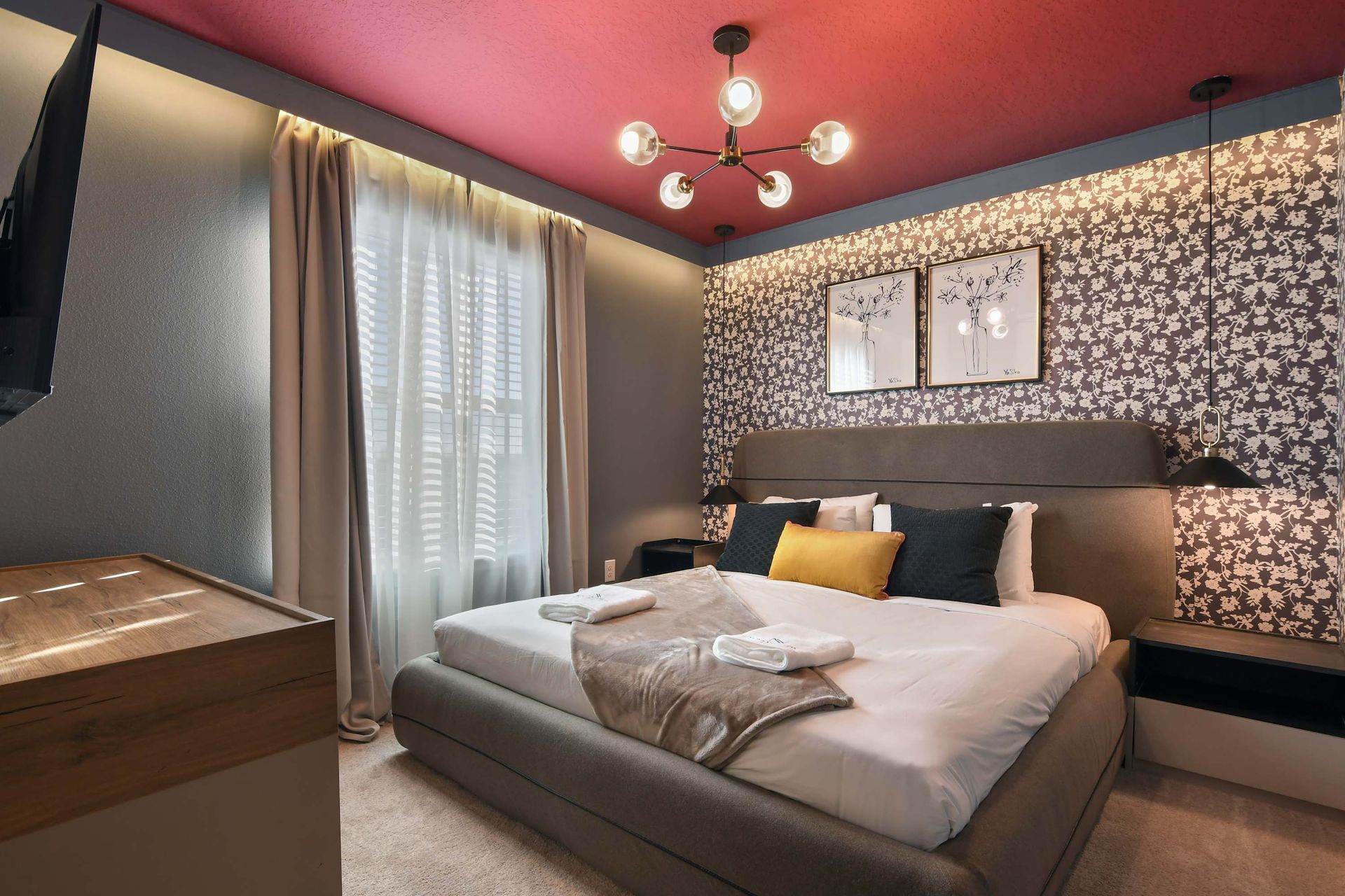 Chic bedroom with floral accents, bold ceiling, and cozy lighting!