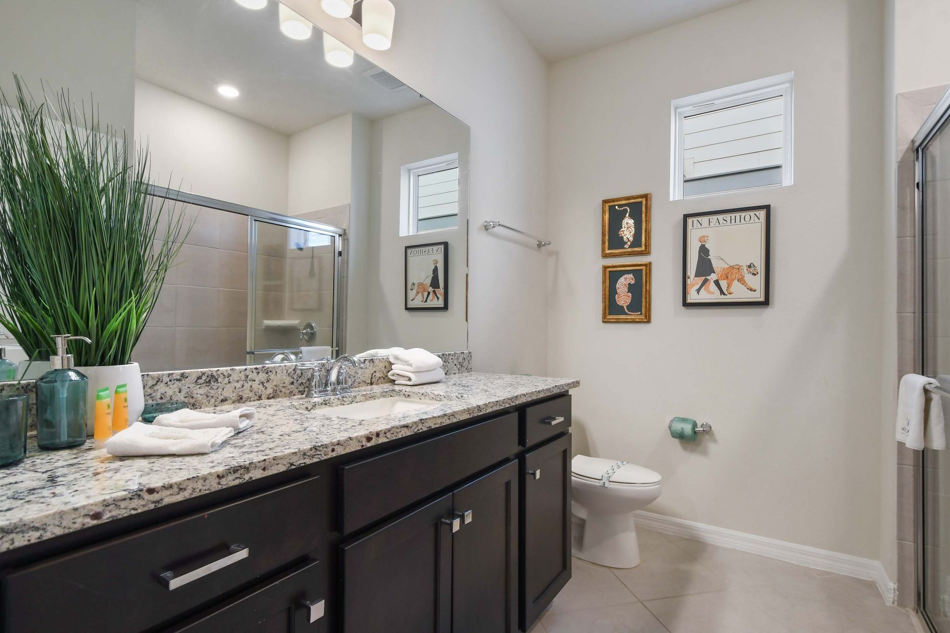 A stylish bathroom featuring a granite-topped double vanity with dark cabinets