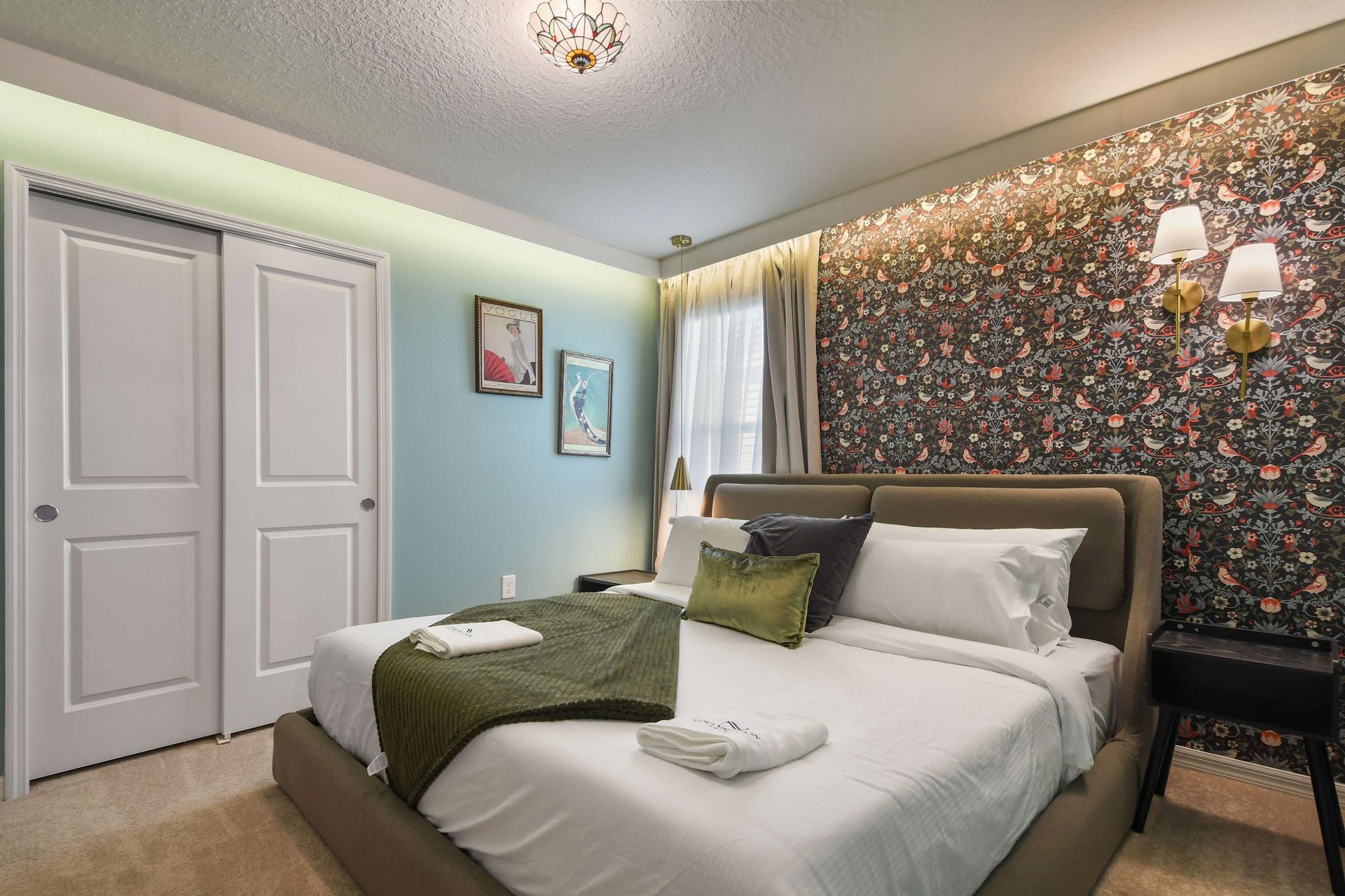 Charming bedroom with floral accent wall, elegant lighting, and style!