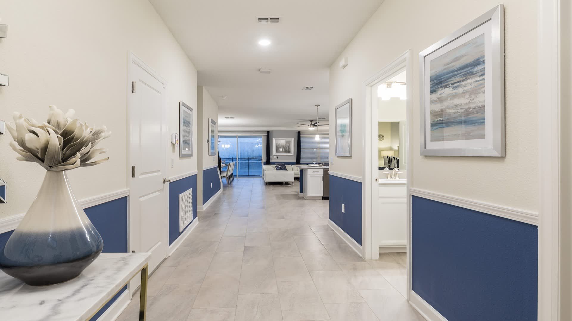 Spacious hallway with coastal décor leads to open living and dining spaces.
