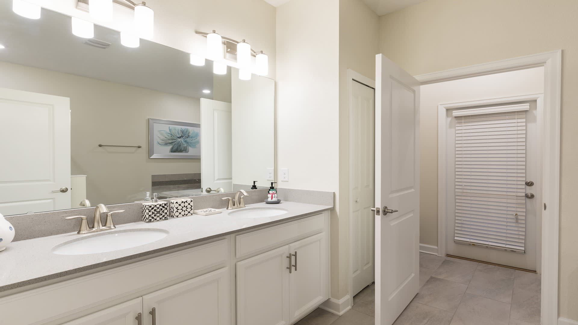 Elegant bathroom with double vanities, ample lighting, and sleek modern finishes.
