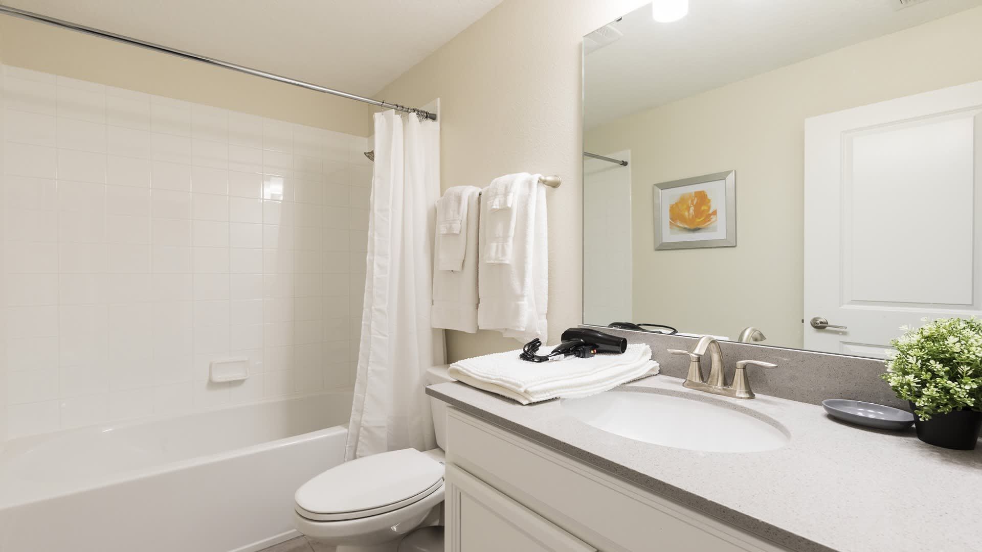 Cozy bathroom with a tub and shower combo, soft lighting, and fresh white towels.