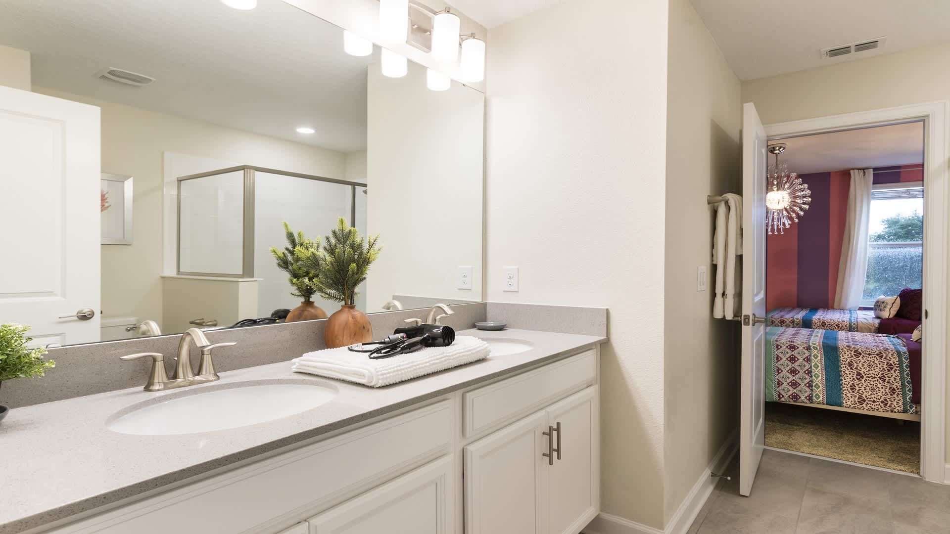 Bright bathroom with double sinks, modern fixtures, and direct access to bedroom.