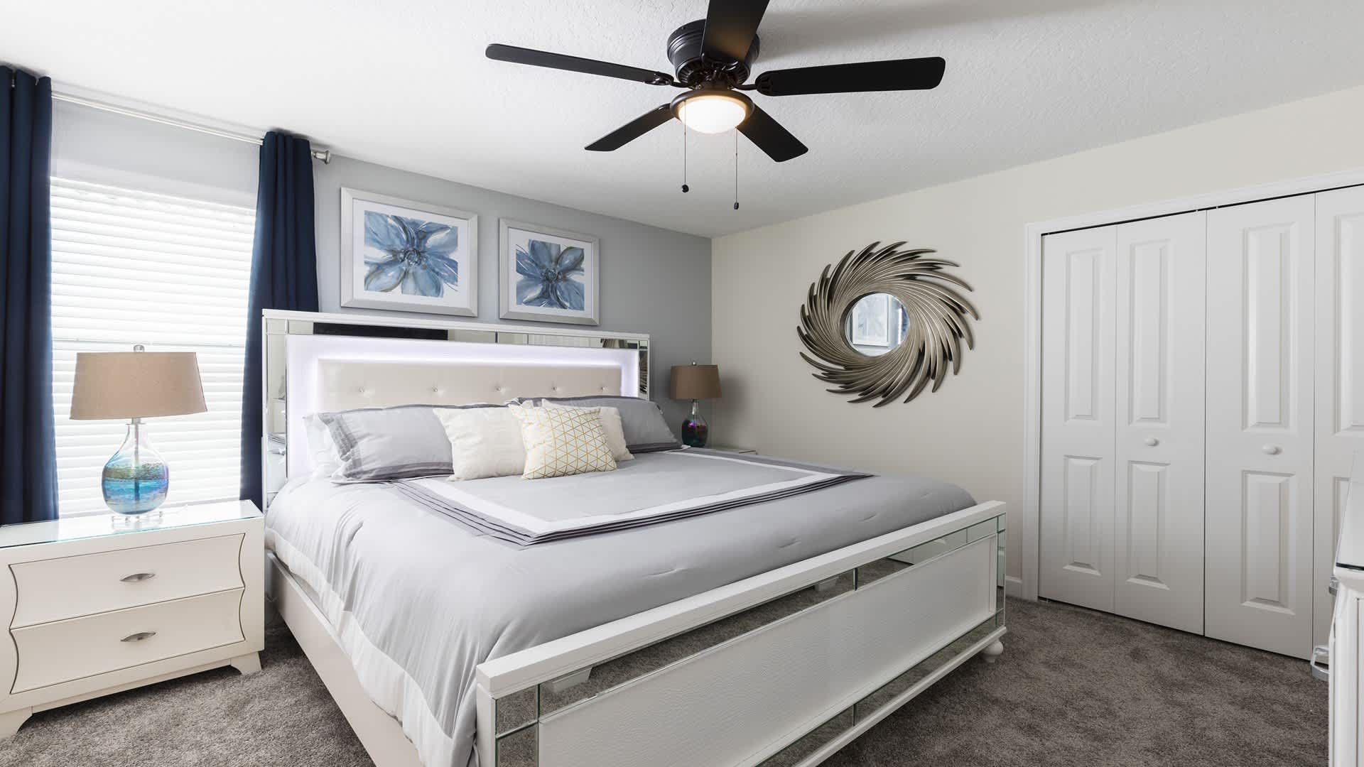 Chic king bedroom with plush bedding, mirrored accents, and relaxing ambiance.