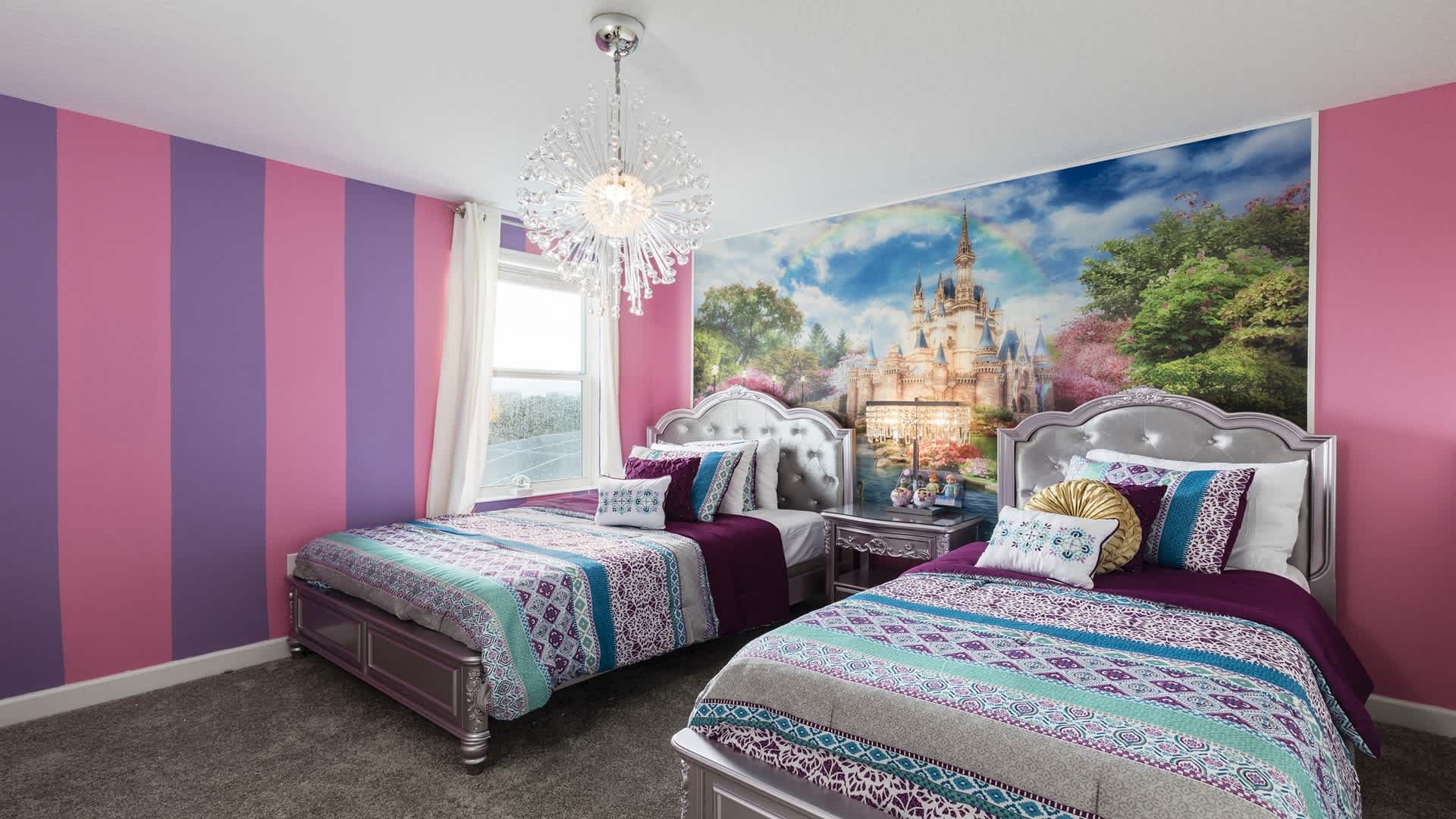 Magical princess room with vibrant colors, sparkling chandelier, and twin beds.