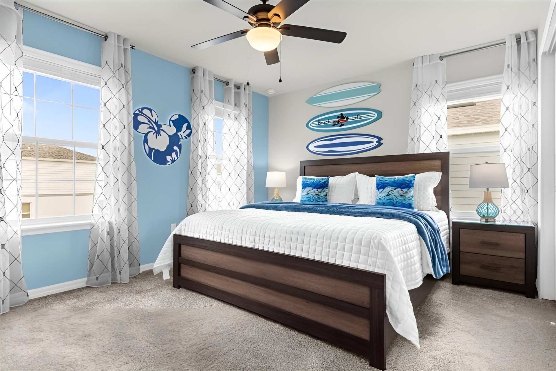 Coastal-inspired bedroom with king bed, surf decor, and plenty of natural light.