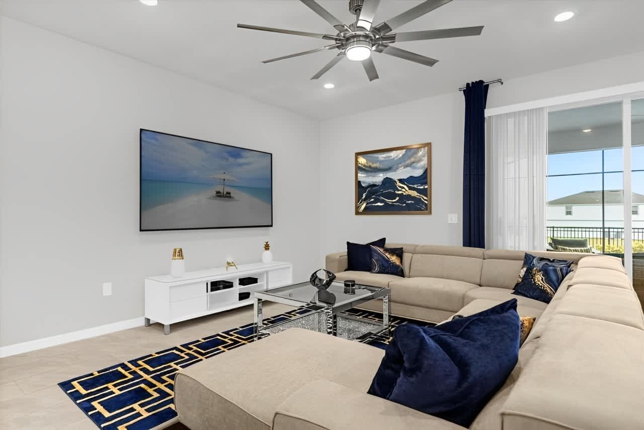 Spacious modern living room with plush sectional, smart TV, and poolside views.