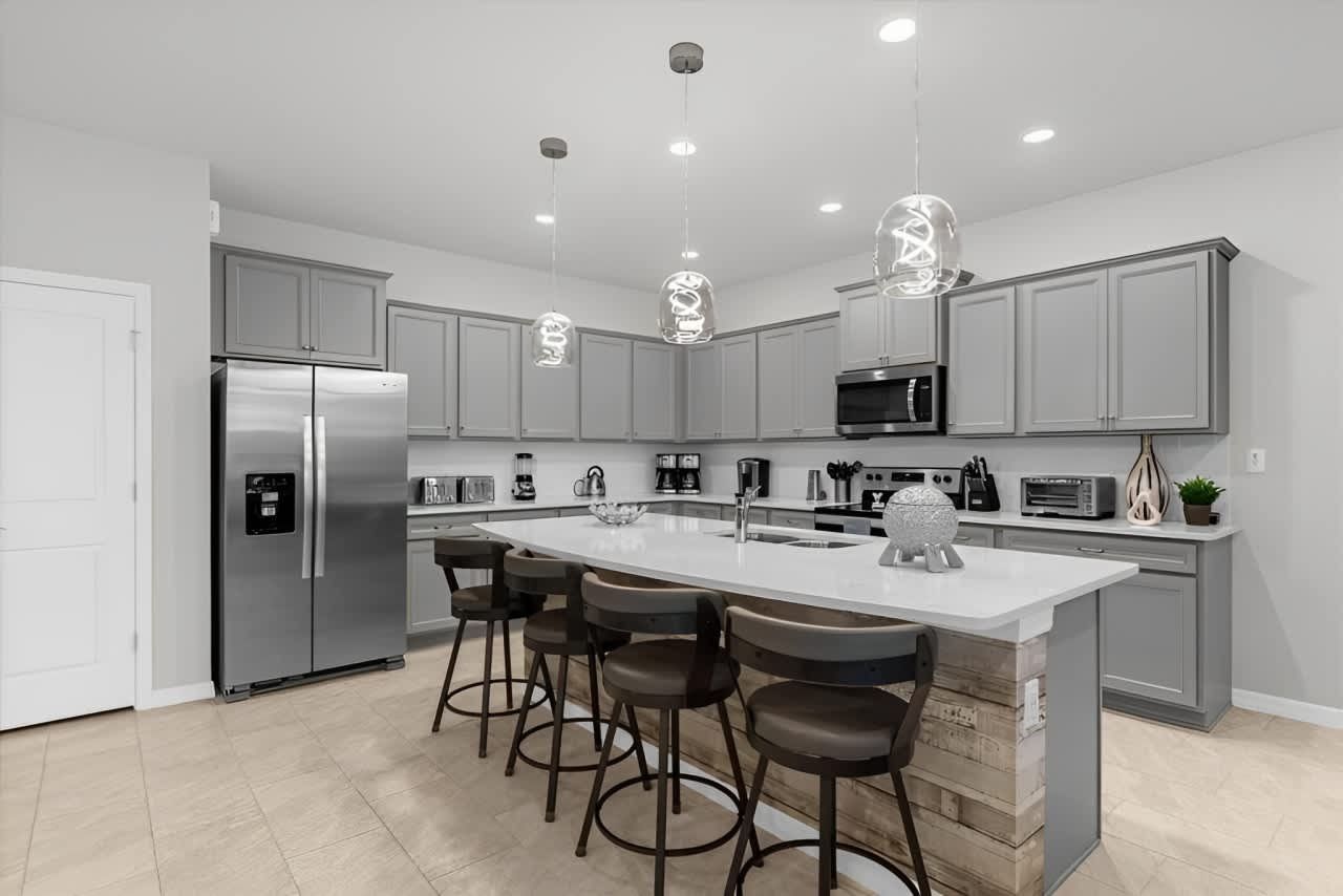 Sleek modern kitchen with gray cabinetry, large island, and stainless steel appliances.