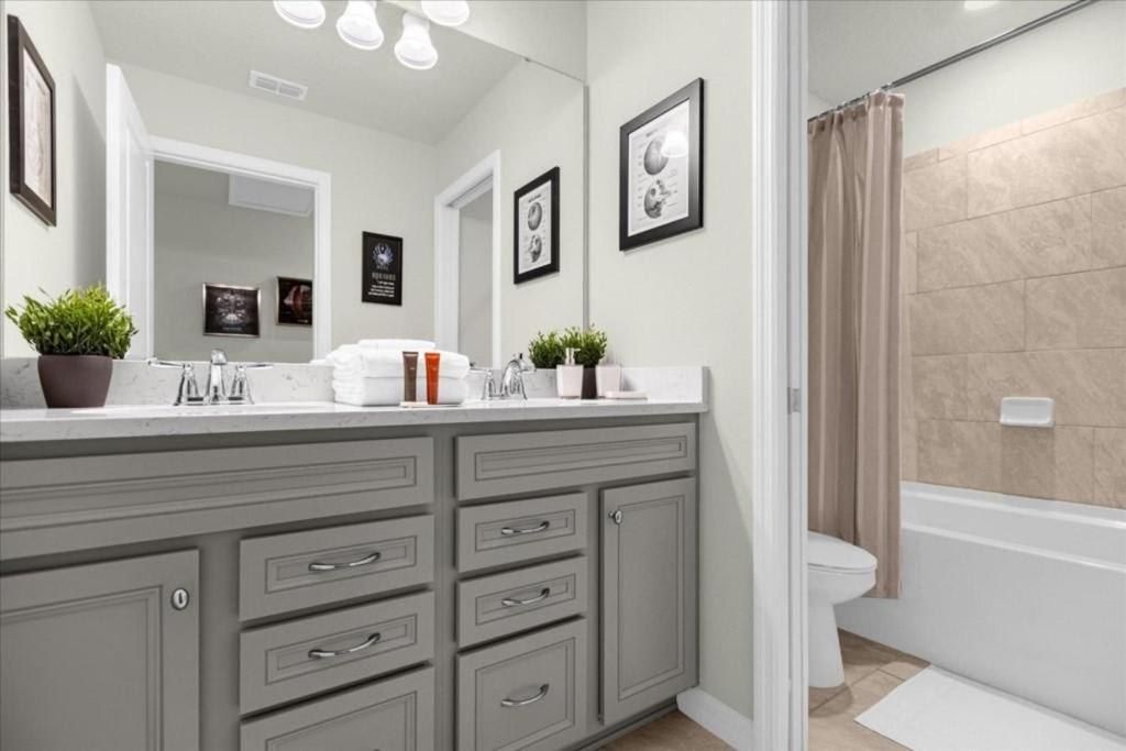 Chic bathroom with gray double vanity, full tub, and stylish black-and-white accents.