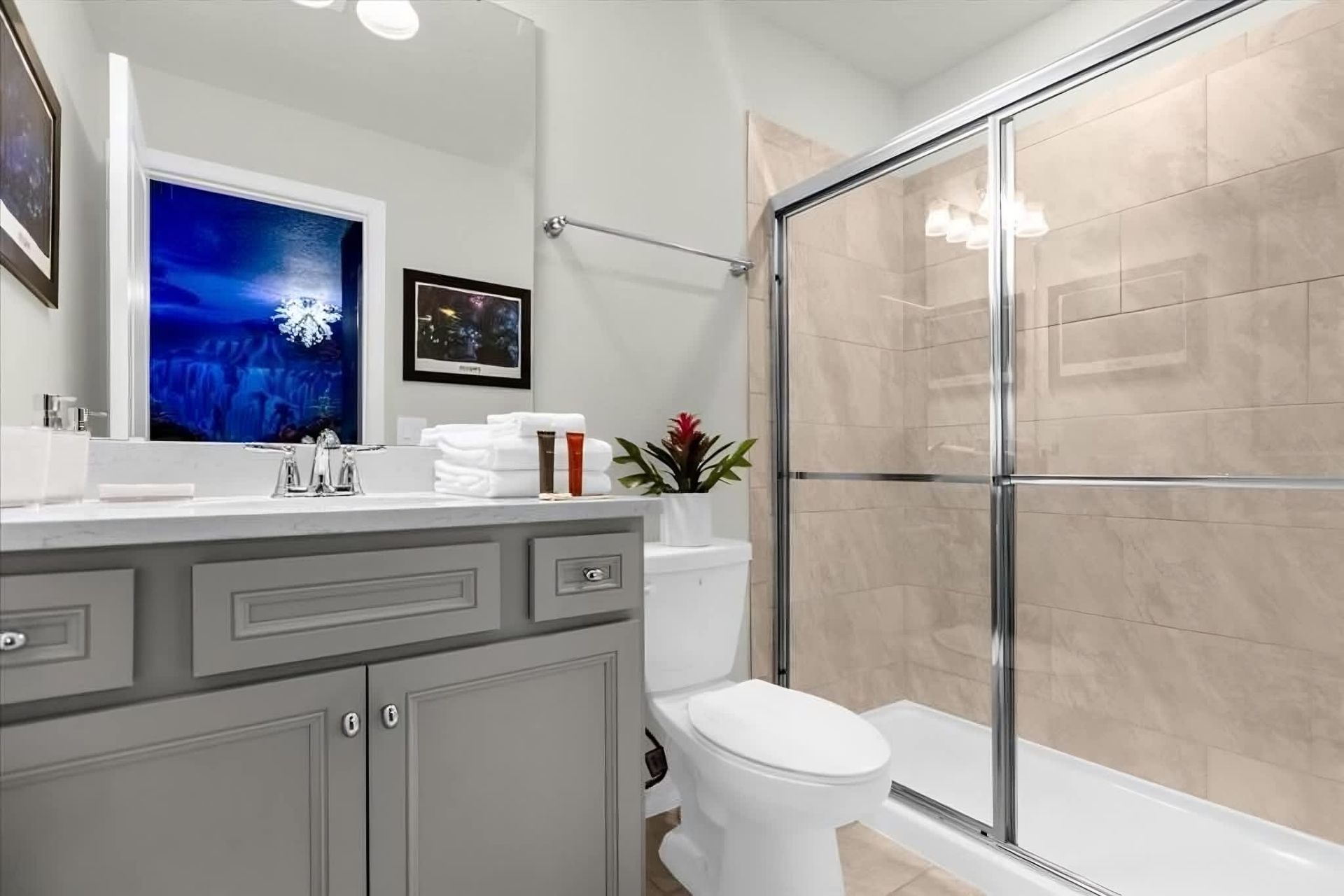 Bright and modern bathroom with glass shower, sleek gray vanity, and themed room view.