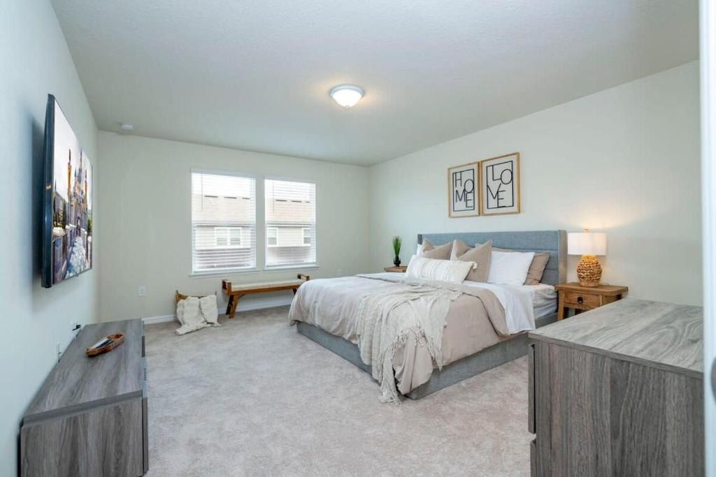 Spacious and airy master bedroom with a large bed, modern decor, and natural light.