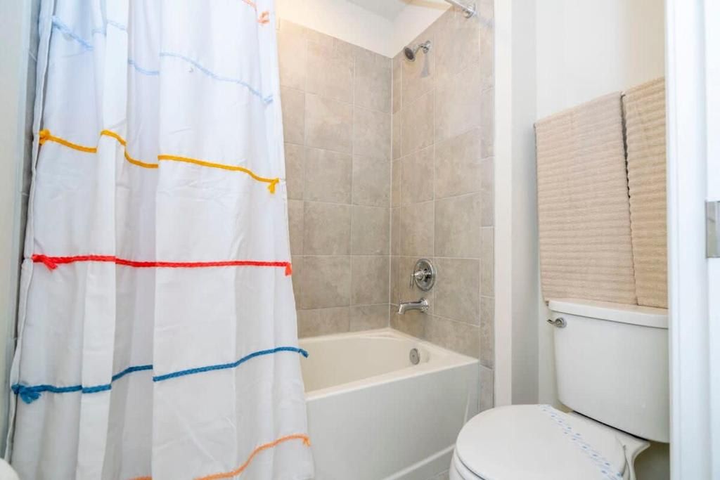 Cozy bathroom with a tiled tub-shower combo and a playful striped curtain.