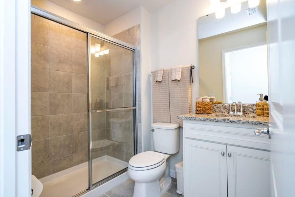 Modern bathroom with walk-in glass shower, granite vanity, and soft neutral tones.