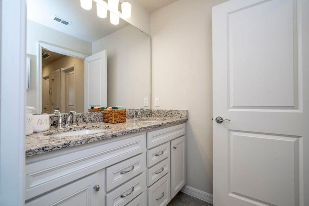 Spacious bathroom with granite double vanity, modern lighting, and sleek style.