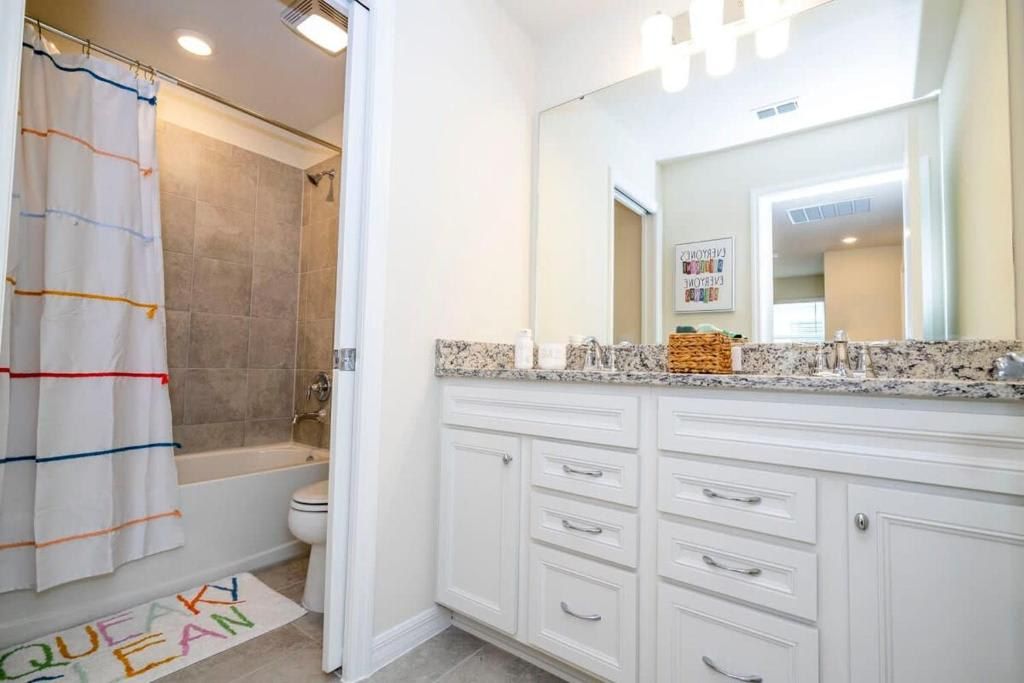 Sparkling clean bathroom with granite counters and a fun, colorful shower vibe.