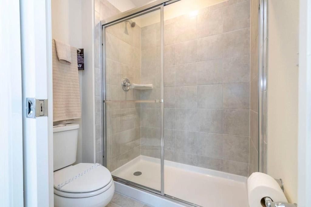 Sleek and simple bathroom with a spacious glass walk-in shower and modern tile.