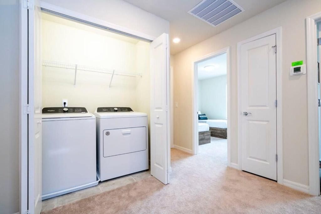 Convenient in-home laundry with washer, dryer, and storage shelf in central hallway.